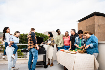 Multigenerational friends having fun doing barbecue at house rooftop - Happy multiracial people cooking together
