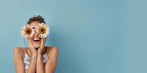 A woman laughs celebrating spring with two flowers in her eyes like glasses. Spring concept, banner, web, advertising. - obrazy, fototapety, plakaty