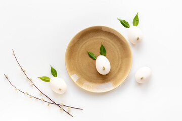 White Easter eggs in shape of bunnies with spring green leaves and willow sprig