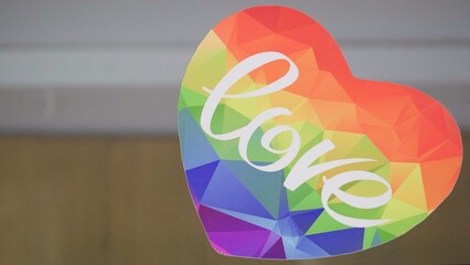 Rainbow heart with Love lettering on neutral background and copy space