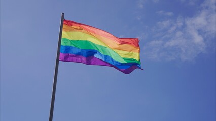 Rainbow LGBT flag waving outdoors with blue sky