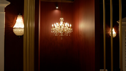 Antique crystal chandelier on a dark background. Beautiful modern chandelier in a red interior.