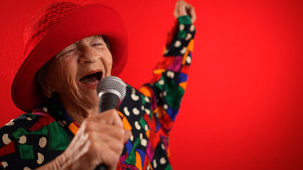 Funny fisheye view of elderly woman singing enthusiastically into a microphone and dancing wearing...