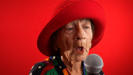 Funny fisheye view of elderly woman singing enthusiastically into a microphone and dancing wearing...