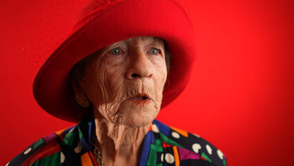 Slow motion saying WOW, a happy fisheye caricature of funny elderly woman with red hat isolated on...