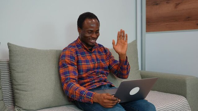 Black man talking to colleague team in video call conference writing note on book with smile face. Man using computer laptop for online meeting