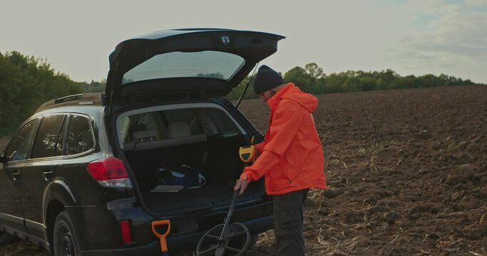 A man enjoys recreational archeology with a metal detector in a field