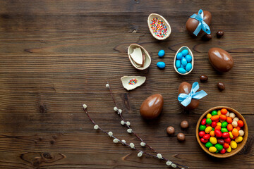 Obraz na płótnie Canvas Chocolate Easter eggs in blue ribbon with sweets on brown wooden background