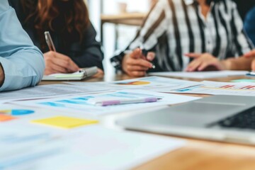 business meeting in session, with team members discussing documents and ideas. One person seems to be explaining a point or presenting, while others listen, reflecting an interactive work environment