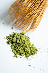 A powdered Green matcha tea with a matcha whisk.