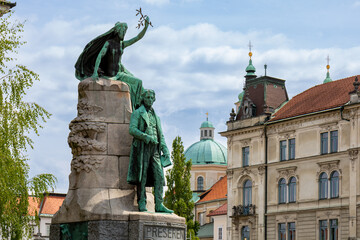 Ljubljana, Slovenia;  Saint Nicholas's Cathedral (Katedrala Sv. Nikolaj) and sculpture located in Prešeren square (Prešernov trg) in front of Franciscan Church of the Annunciation - obrazy, fototapety, plakaty