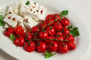 baked cherry tomatoes , with cheese, and spices, on a white plate, homemade, no people,