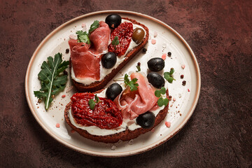 sandwiches with cheese and prosciutto, dried tomatoes and olives, breakfast on a plate,