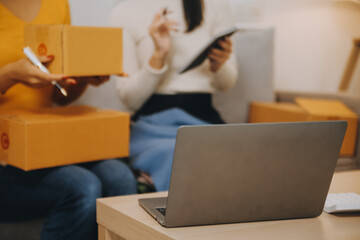 Asian SME business women use laptop computer checking customer order online shipping boxes at home....
