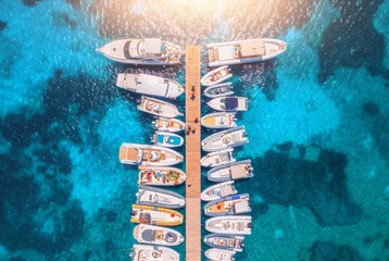 Aerial view of boats and luxure yachts in dock at sunset in summer in Sardinia, Italy. Colorful landscape with sailboats and motorboats in sea bay, jatty, clear blue sea. Top view of harbor. Travel - 758213147