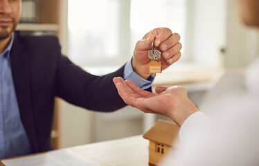 Close up photo of professional man realtor agent giving house key to a customer sitting in office...