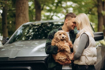 happy young couple with a dog in the forest