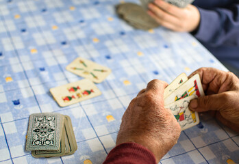 Elder hands playing cards on a blue table