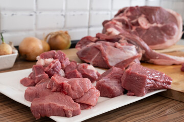 Close up of peases of meat, cutting fresh raw meat on  board in white kitchen. Preparing pork meat,...