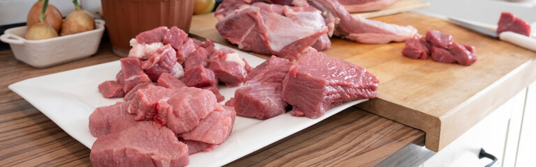 Different tipes of meat, cutting fresh raw meat on  board in white kitchen. Preparing pork meat, cooking. Banner