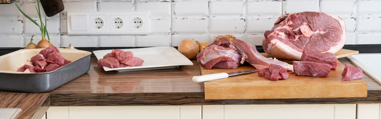 Different tipes of meat,  cutting fresh raw meat on  board in white kitchen. Preparing pork meat,...