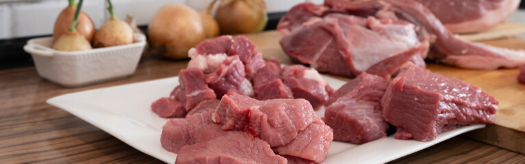 Peases of meat, cutting fresh raw meat on  board in white kitchen. Banner, Preparing pork meat, cooking