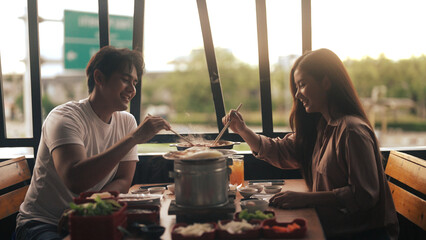 Asian couple eating barbecue in a restaurant - obrazy, fototapety, plakaty