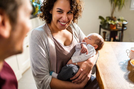 New parents with their baby at the dining table - Powered by Adobe