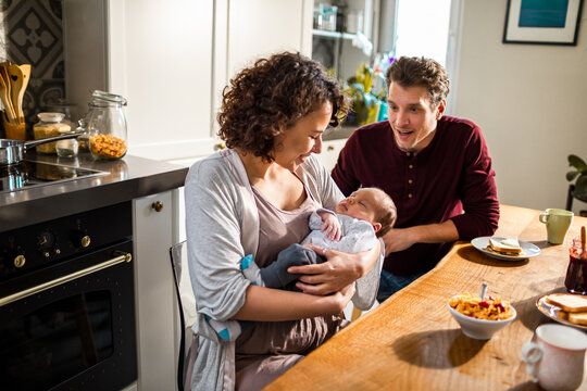 New parents with their baby at the dining table - Powered by Adobe