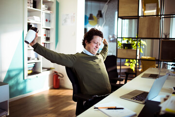 Relaxed businessman stretching in office with coffee mug