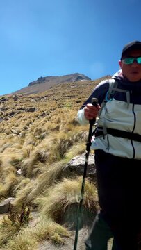 A man with a backpack takes a hiking trip to the top of a mountain, symbolizing overcoming challenges and pursuing goals.