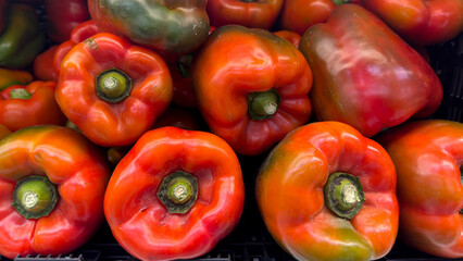 Fresh and juicy red peppers, ideal for a healthy diet. A group of bright red peppers, stacked on a market counter. Concept of healthy and vegan food, red and green peppers