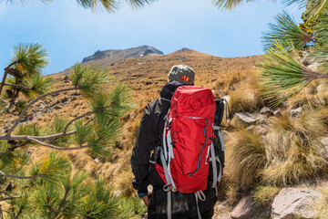 Man with backpack observes the top of a mountain, symbolizing motivation and goal achievement.