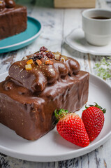 Gastronomic photography of a delicious chocolate dessert in close-up blurring the background on a white plate and a red strawberry
