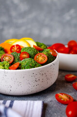 Food photography, a salad of tomatoes, cobs, broccoli, lettuce and a bunch of cherry tomatoes in the background

