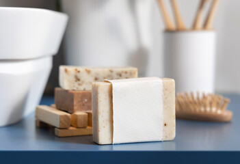 Soap bar with blank label near hygiene products on blue bathroom countertop close up, mockup