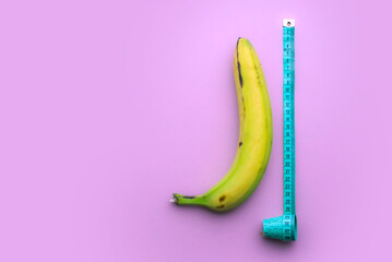 Banana with measuring tape on pink background. Men penis size concept. Flat lay, top view, copy...