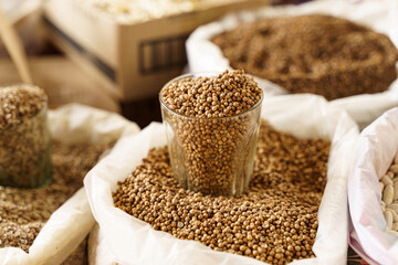 There is a glass glass with coriander in an open bag of spices.