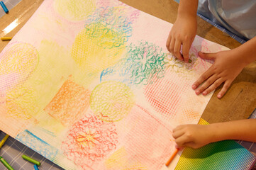 Top view kids drawing with pastel color pencils on cardboard paper during art class lesson in a creative workshop.