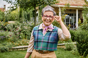 Obraz premium sophisticated mature joyful woman with short hair smiling at camera near her house in England