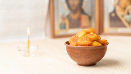 Holy Week, End, Palm Sunday, Good Friday, Easter Sunday Concept. Orthodox food in Great Christian Lent, Lenten food on a wooden table against the background of Orthodox icons. a lighted candle in lamp