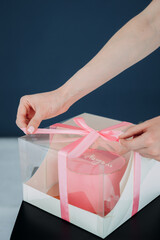 The image shows a person opening a pink box indoors 6230.