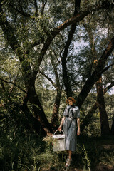 Naklejka na ściany i meble The image shows a person carrying a basket outdoors in a forest setting during the summer. 6333