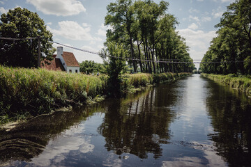 Fototapeta na wymiar Familie radelt während einer Radreise auf einem Radweg entlang eines Kanals in Flandern, Belgien