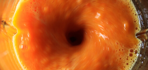 Photograph of blender in motion making orange juice. Food preparation concept