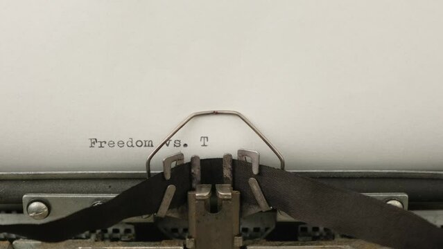 typing motivational announcement Freedom vs. Tyranny on a vintage typewriter close-up