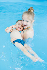 Fototapeta na wymiar Little boy and girl swim in the pool. Swimming pool for children. Children's pool