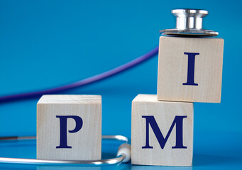 PMI - acronym on wooden large cubes on blue background with stethoscope
