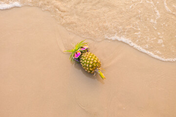 Funny pineapples in stylish sunglasses on the sand..