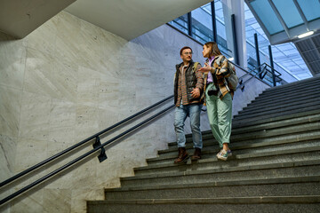 Engrossed in conversation, a couple ascends the train station stairs, the warm glow of the city...